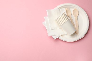 Photo of Set of disposable tableware on pink background, top view. Space for text