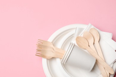 Photo of Set of disposable tableware on pink background, top view. Space for text