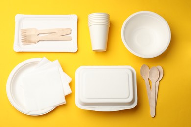 Photo of Set of disposable tableware on yellow background, flat lay