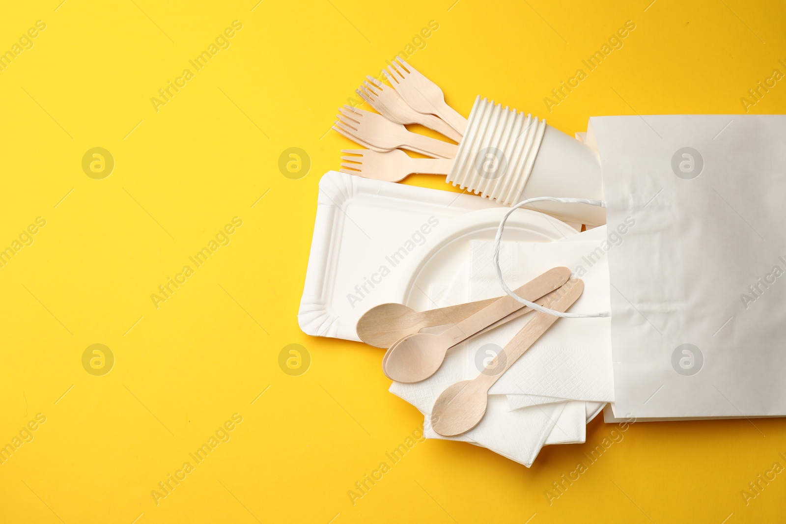 Set of disposable tableware on yellow background, flat lay. Space for text Photo of Set of disposable tableware on yellow background, flat lay. Space for text