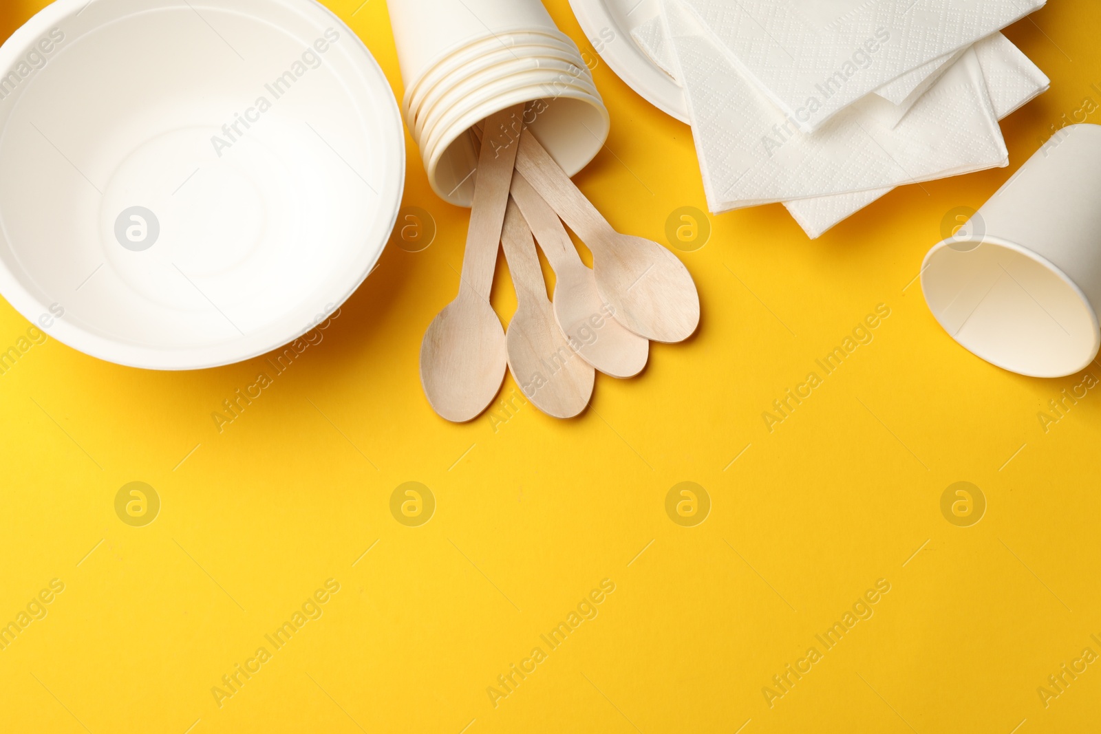 Set of disposable tableware on yellow background, flat lay. Space for text Photo of Set of disposable tableware on yellow background, flat lay. Space for text