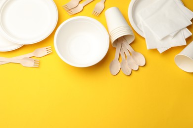 Photo of Set of disposable tableware on yellow background, flat lay. Space for text
