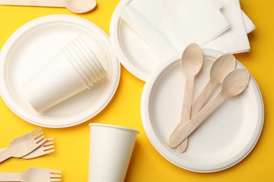 Photo of Set of disposable tableware on yellow background, flat lay