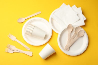 Photo of Set of disposable tableware on yellow background, flat lay