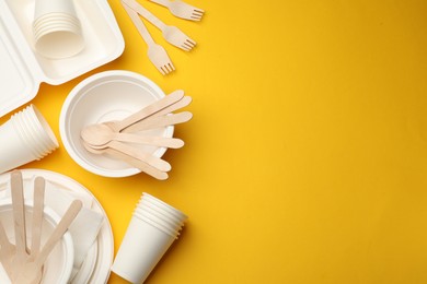 Photo of Set of disposable tableware on yellow background, flat lay. Space for text