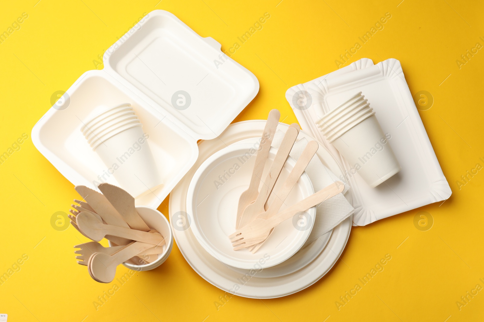 Set of disposable tableware on yellow background, flat lay Photo of Set of disposable tableware on yellow background, flat lay