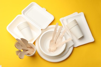 Photo of Set of disposable tableware on yellow background, flat lay