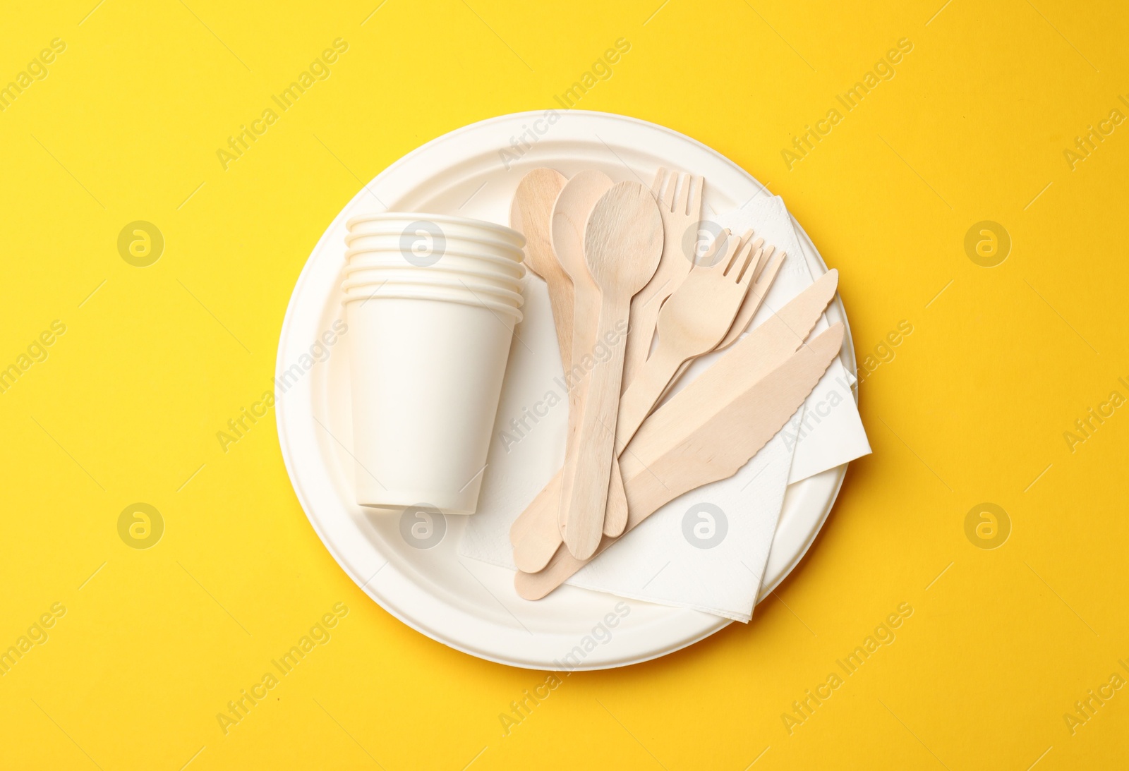 Set of disposable tableware on yellow background, top view Photo of Set of disposable tableware on yellow background, top view