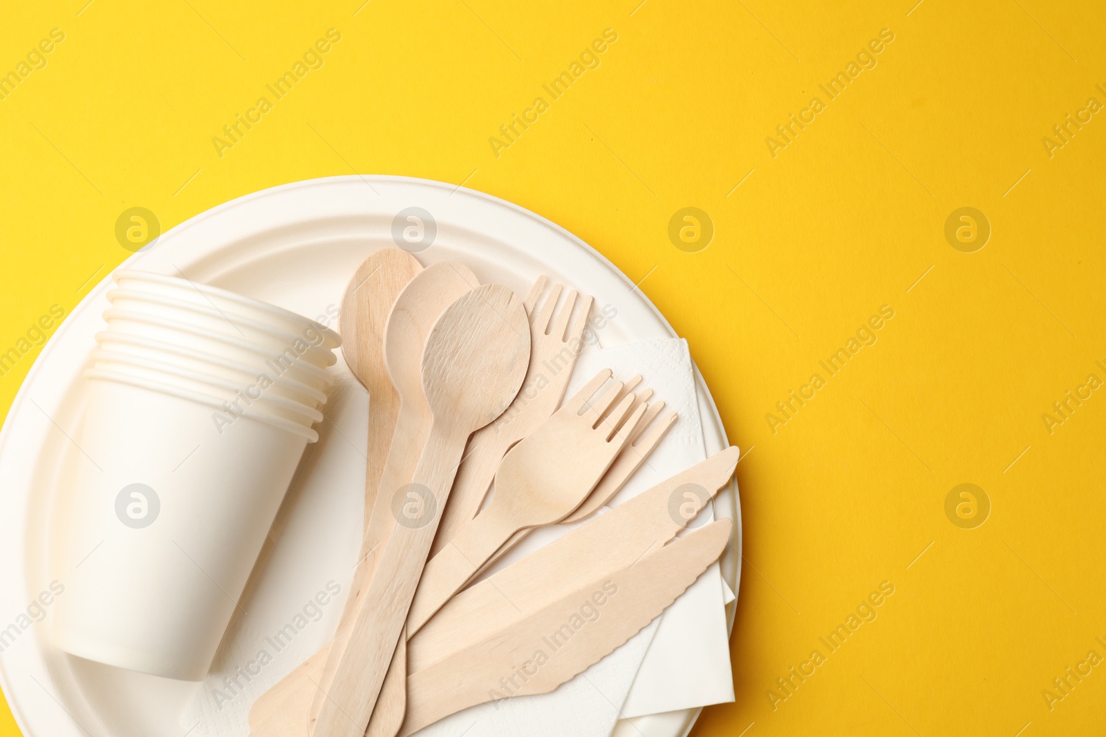 Set of disposable tableware on yellow background, top view. Space for text Photo of Set of disposable tableware on yellow background, top view. Space for text