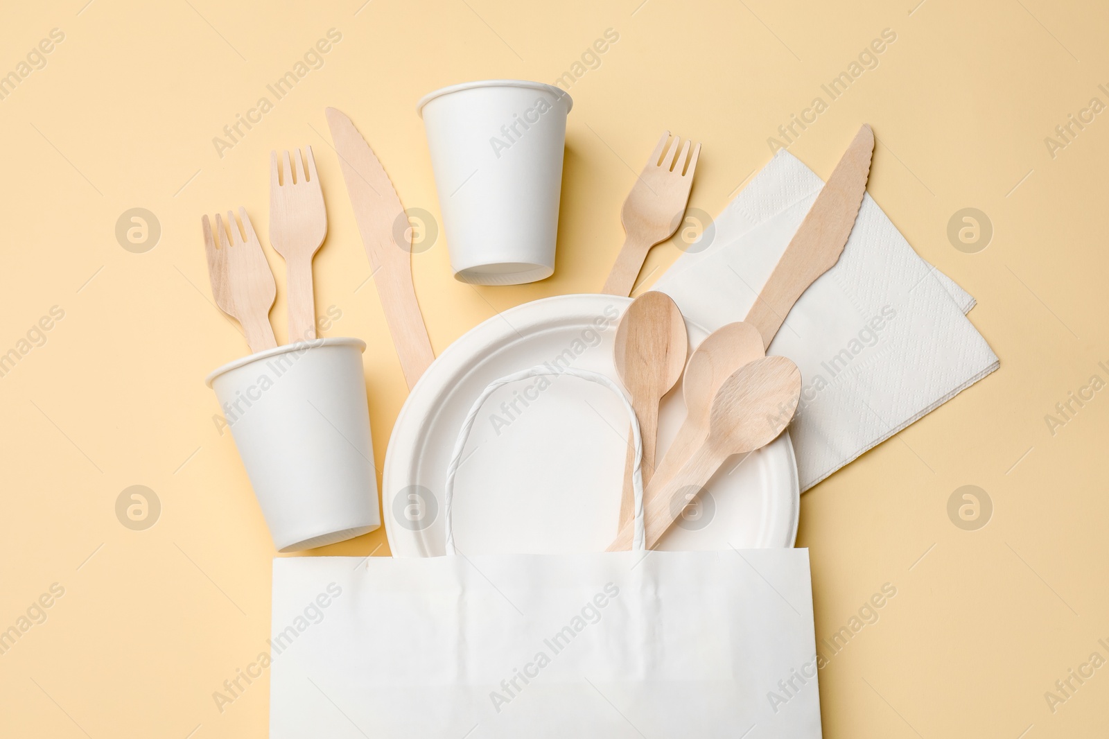 Set of disposable tableware on beige background, flat lay Photo of Set of disposable tableware on beige background, flat lay