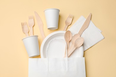 Photo of Set of disposable tableware on beige background, flat lay