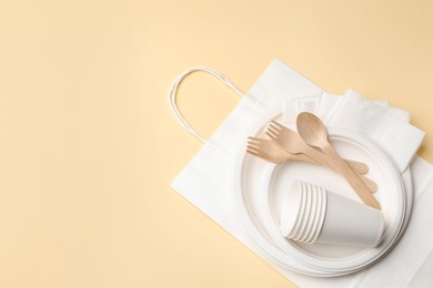 Photo of Set of disposable tableware on beige background, top view. Space for text