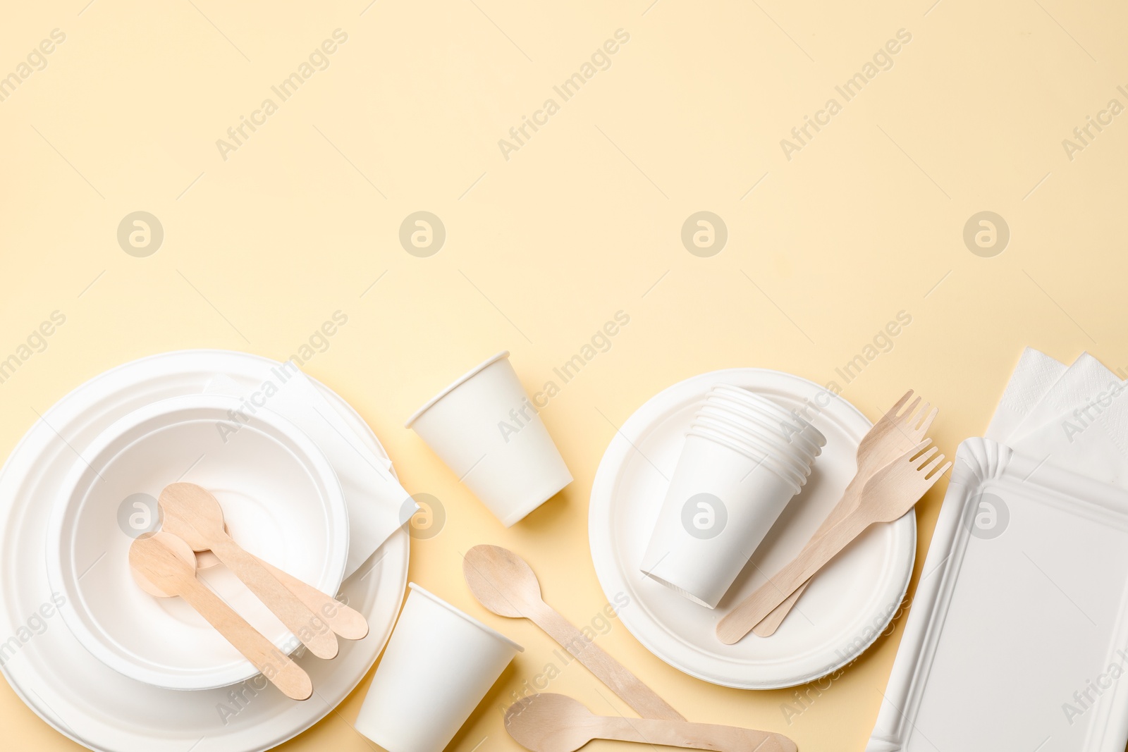 Set of disposable tableware on beige background, flat lay. Space for text Photo of Set of disposable tableware on beige background, flat lay. Space for text