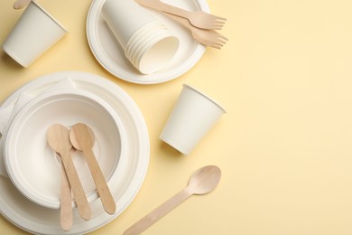 Photo of Set of disposable tableware on beige background, flat lay. Space for text