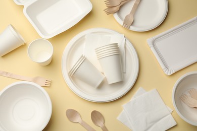 Photo of Set of disposable tableware on beige background, flat lay