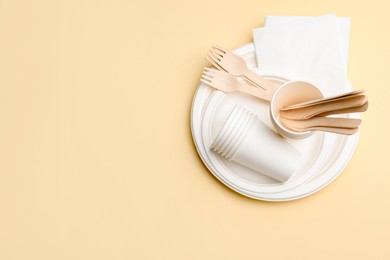 Photo of Set of disposable tableware on beige background, top view. Space for text