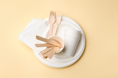 Photo of Set of disposable tableware on beige background, top view
