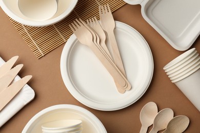 Photo of Set of disposable tableware on brown background, flat lay