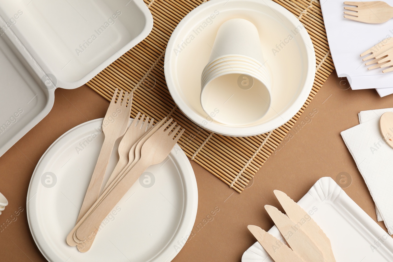 Set of disposable tableware on brown background, flat lay Photo of Set of disposable tableware on brown background, flat lay