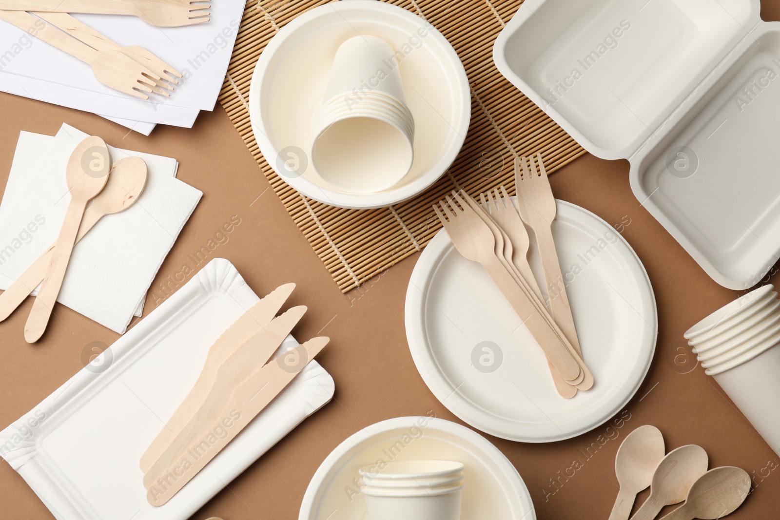 Set of disposable tableware on brown background, flat lay Photo of Set of disposable tableware on brown background, flat lay