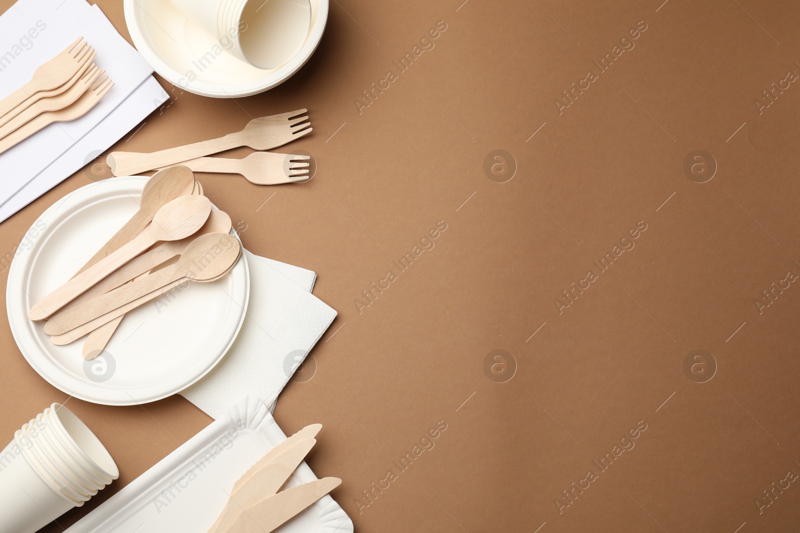 Set of disposable tableware on brown background, flat lay. Space for text Photo of Set of disposable tableware on brown background, flat lay. Space for text