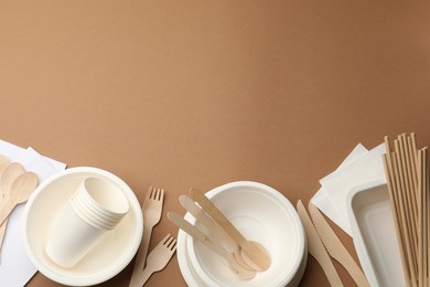 Photo of Set of disposable tableware on brown background, flat lay. Space for text