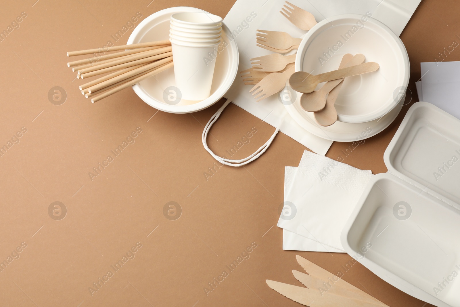 Set of disposable tableware on brown background, flat lay. Space for text Photo of Set of disposable tableware on brown background, flat lay. Space for text
