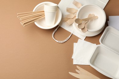 Photo of Set of disposable tableware on brown background, flat lay. Space for text