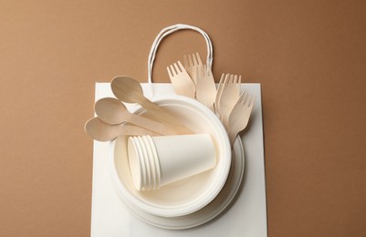 Photo of Set of disposable tableware on brown background, top view