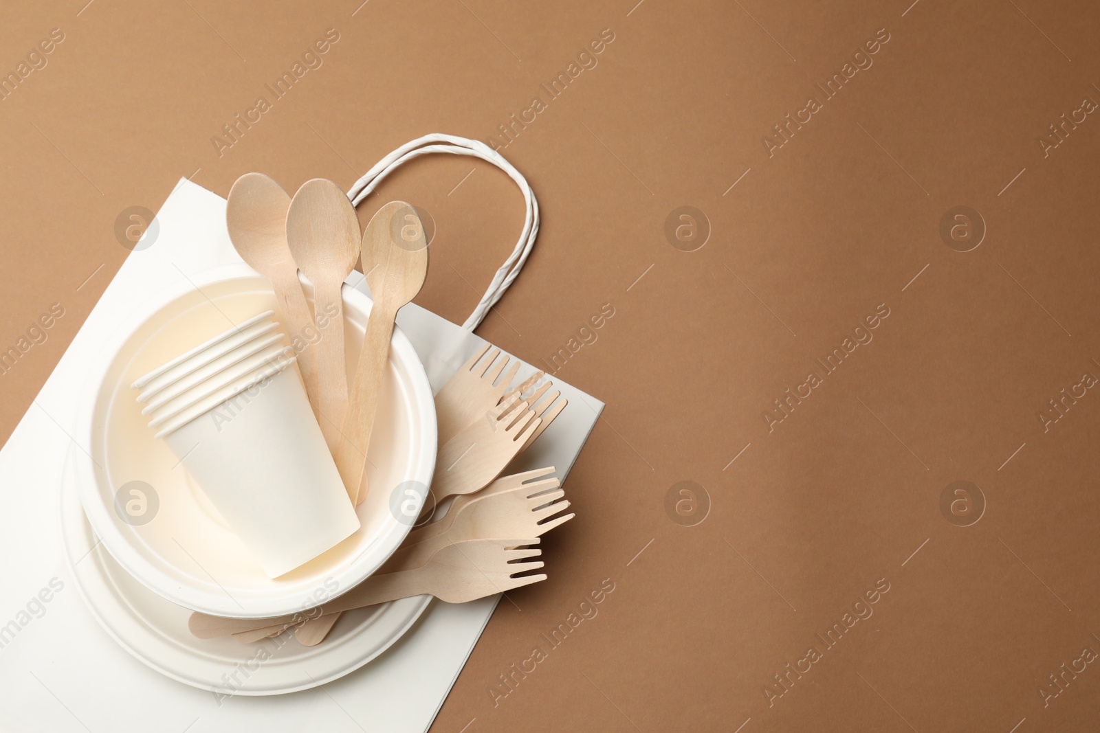 Set of disposable tableware on brown background, top view. Space for text Photo of Set of disposable tableware on brown background, top view. Space for text