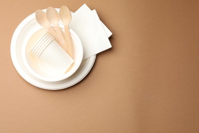 Photo of Set of disposable tableware on brown background, top view. Space for text