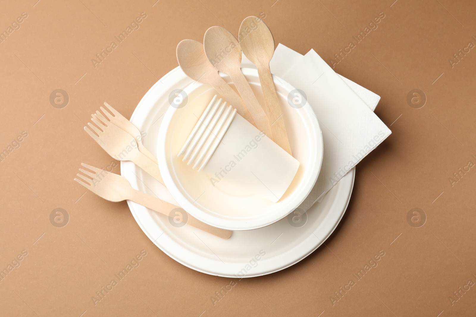 Set of disposable tableware on brown background, top view Photo of Set of disposable tableware on brown background, top view