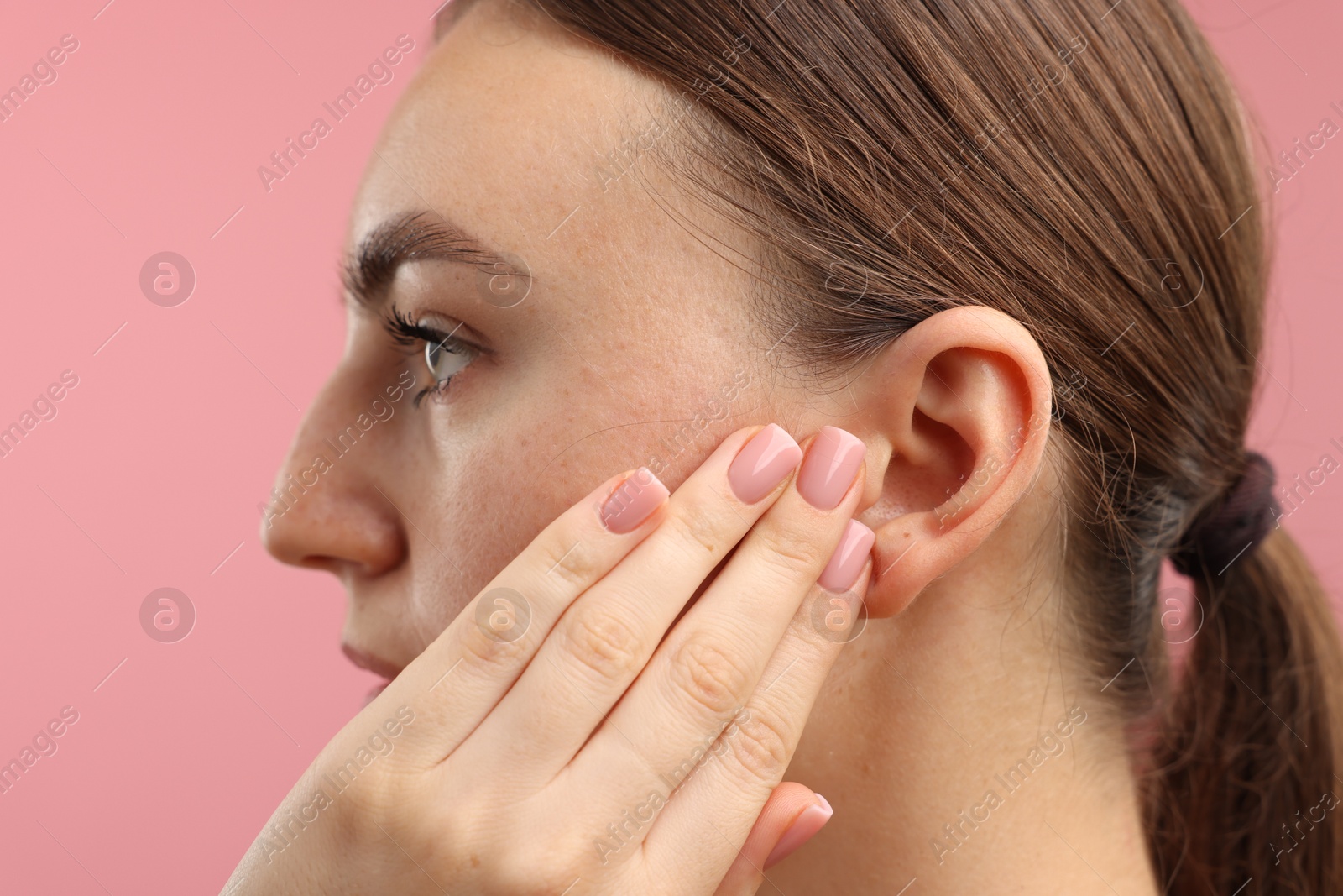 Photo of Sound. Woman touching his ear on pink background, closeup