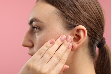 Photo of Sound. Woman touching his ear on pink background, closeup