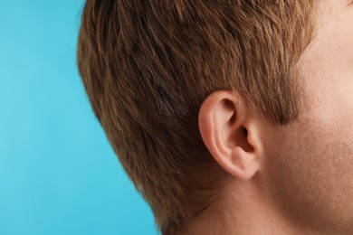 Photo of Sound. Man on light blue background, closeup. Space for text