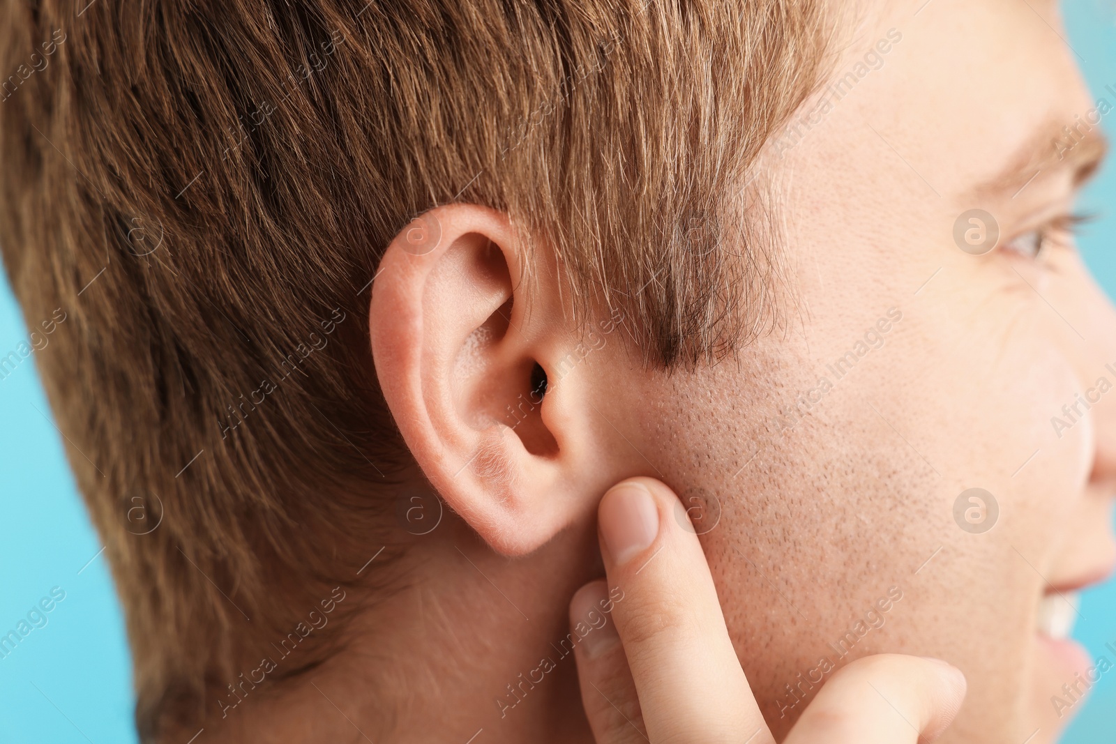 Photo of Sound. Man on light blue background, closeup