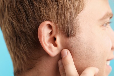 Photo of Sound. Man on light blue background, closeup