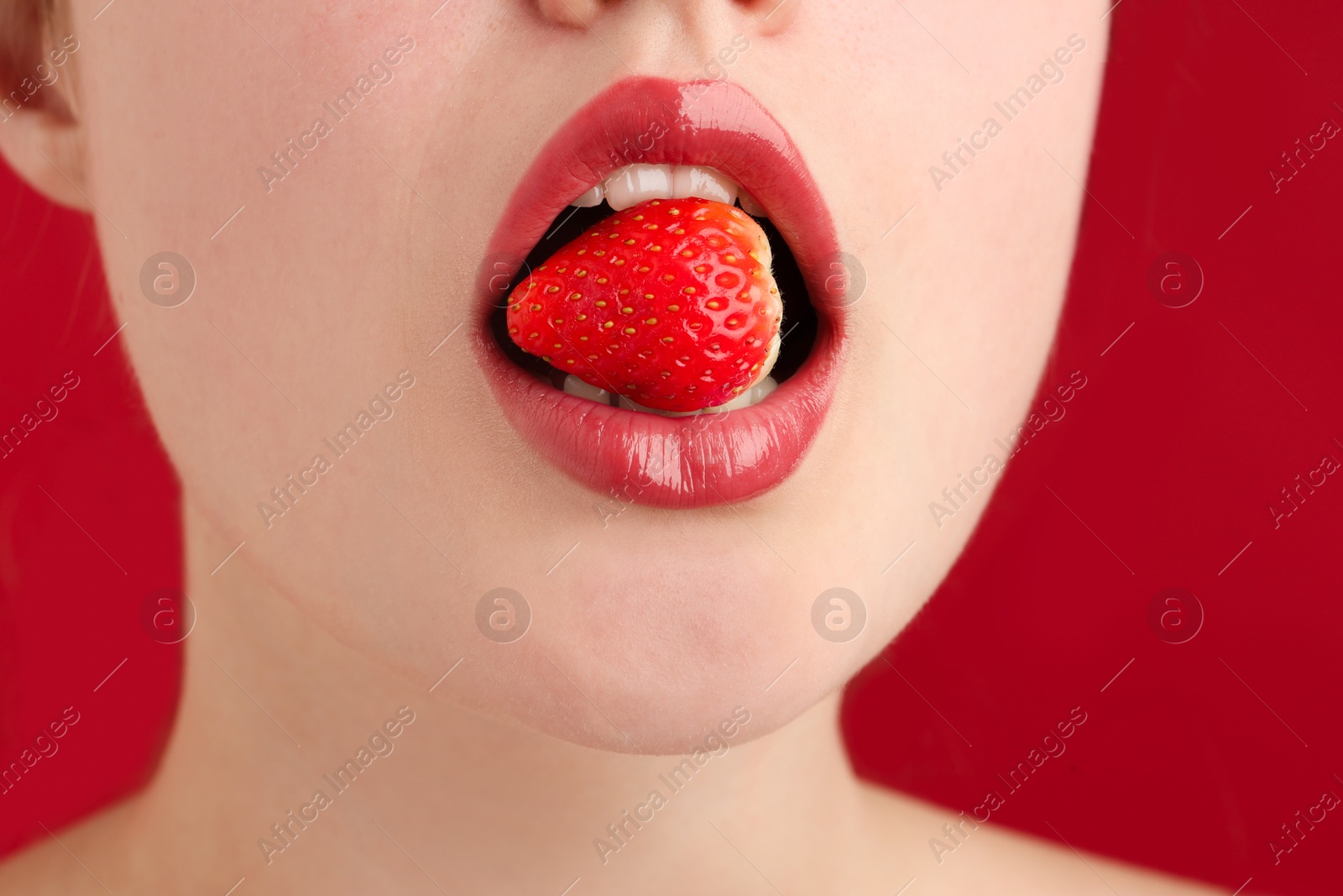 Woman with beautiful lips makeup and strawberry on red background, closeup Photo of Woman with beautiful lips makeup and strawberry on red background, closeup