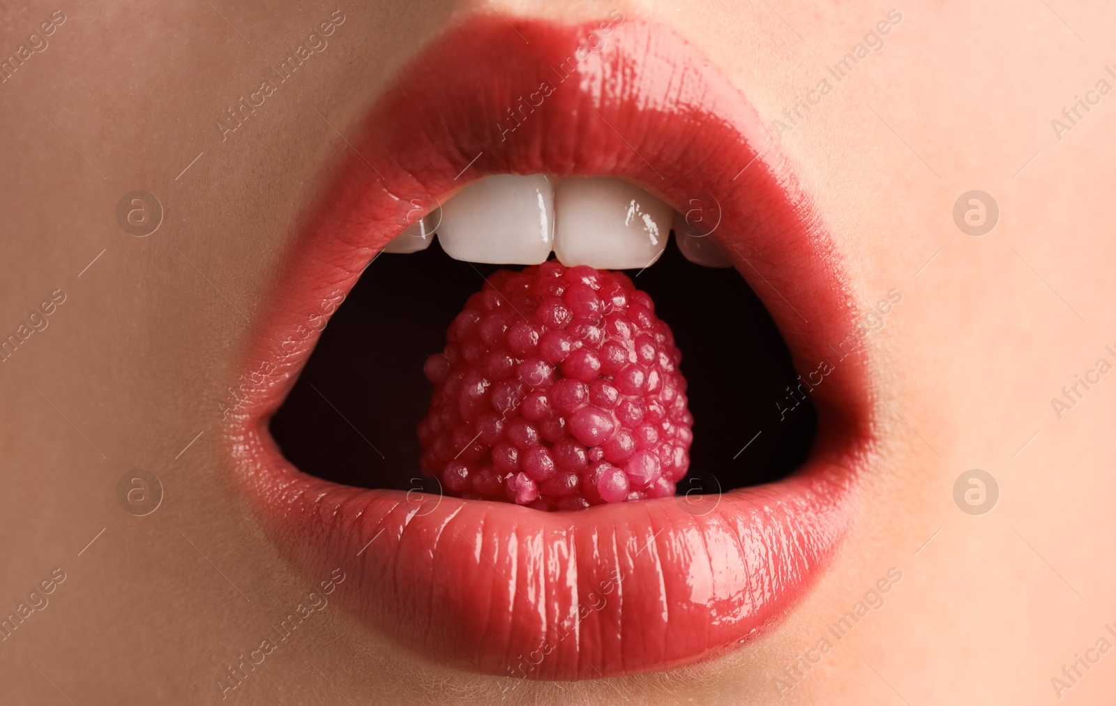 Woman with beautiful lips makeup and raspberry candy, closeup Photo of Woman with beautiful lips makeup and raspberry candy, closeup