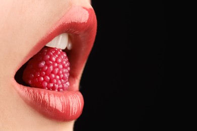 Photo of Woman with beautiful lips makeup and raspberry candy on black background, closeup. Space for text