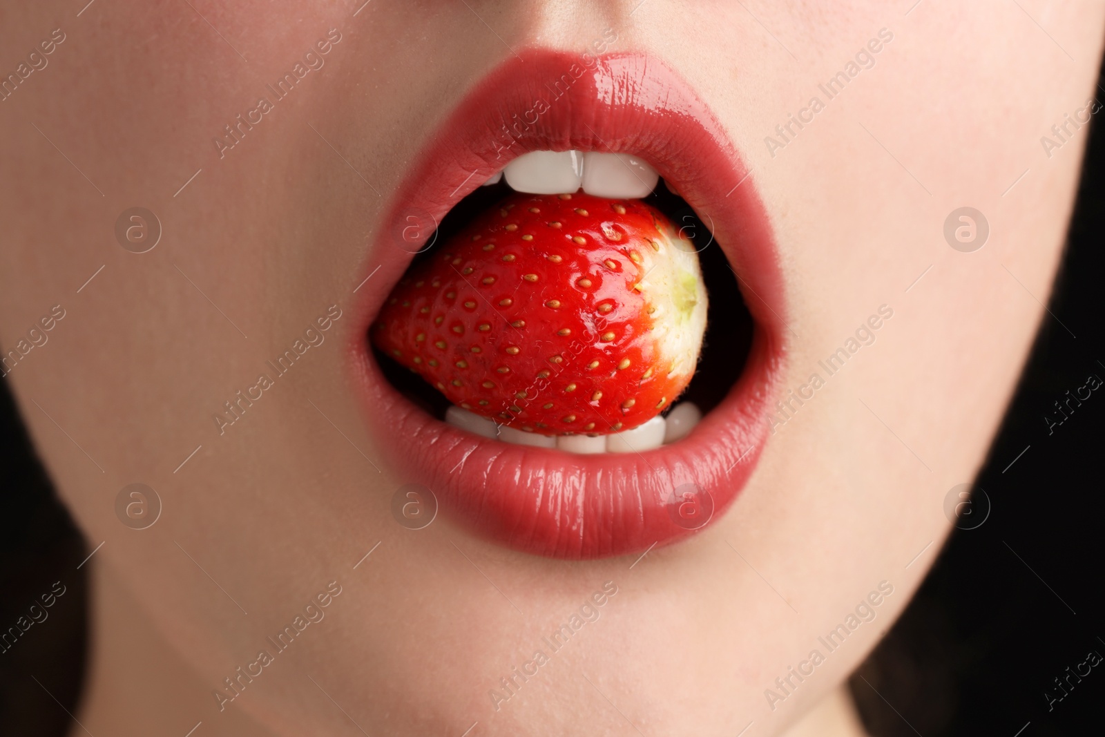 Woman with beautiful lips makeup and strawberry on black background, closeup Photo of Woman with beautiful lips makeup and strawberry on black background, closeup