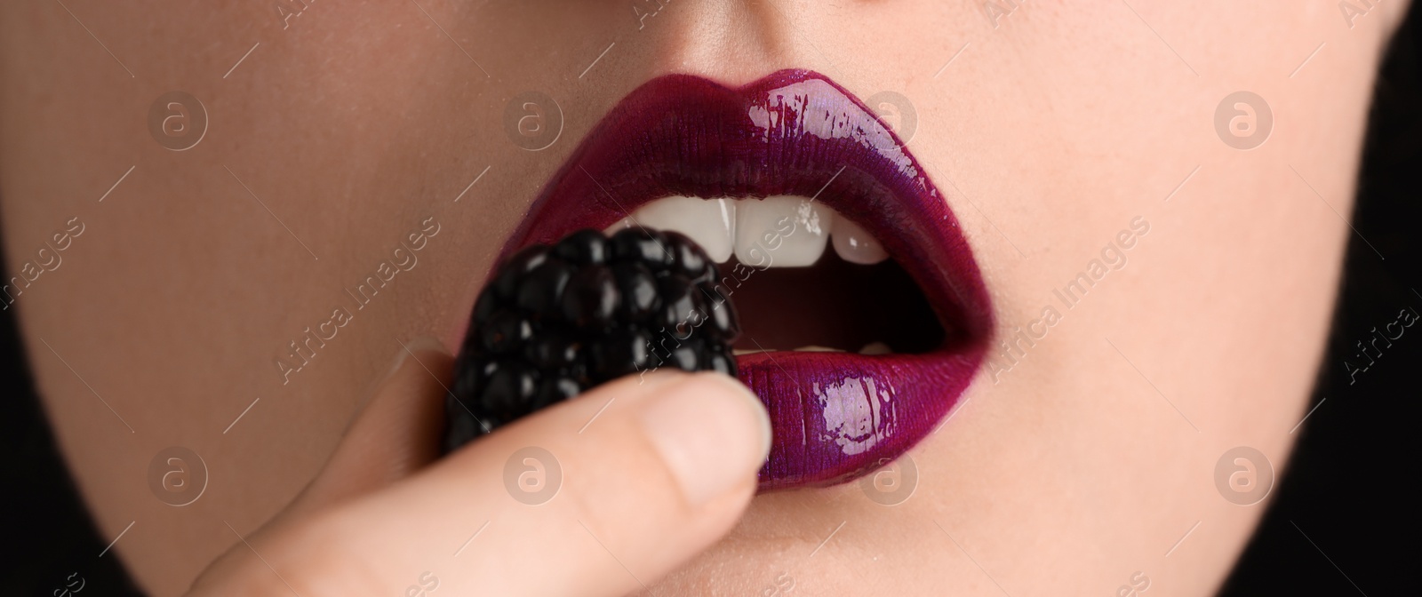 Woman with beautiful lips makeup and blackberry on black background, closeup Photo of Woman with beautiful lips makeup and blackberry on black background, closeup