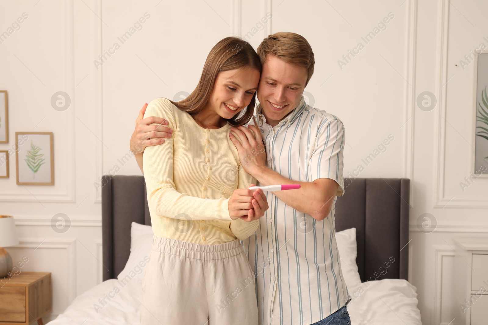 Photo of Happy couple with pregnancy test in bedroom