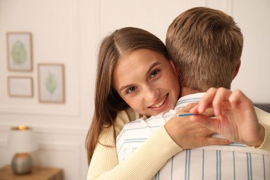 Photo of Happy couple with positive pregnancy test at home, space for text