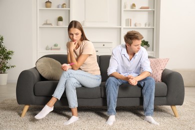Photo of Worried couple with pregnancy test on sofa at home