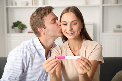Photo of Happy couple with pregnancy test at home