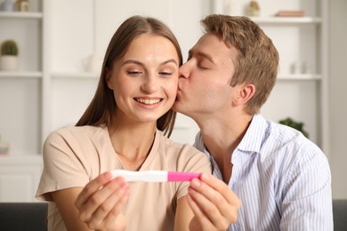 Photo of Happy couple with pregnancy test at home