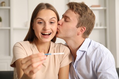 Photo of Happy couple with pregnancy test at home