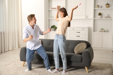Photo of Happy couple with pregnancy test at home