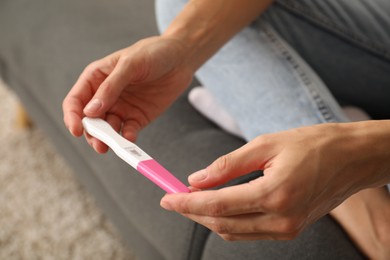 Photo of Woman with pregnancy test at home, closeup
